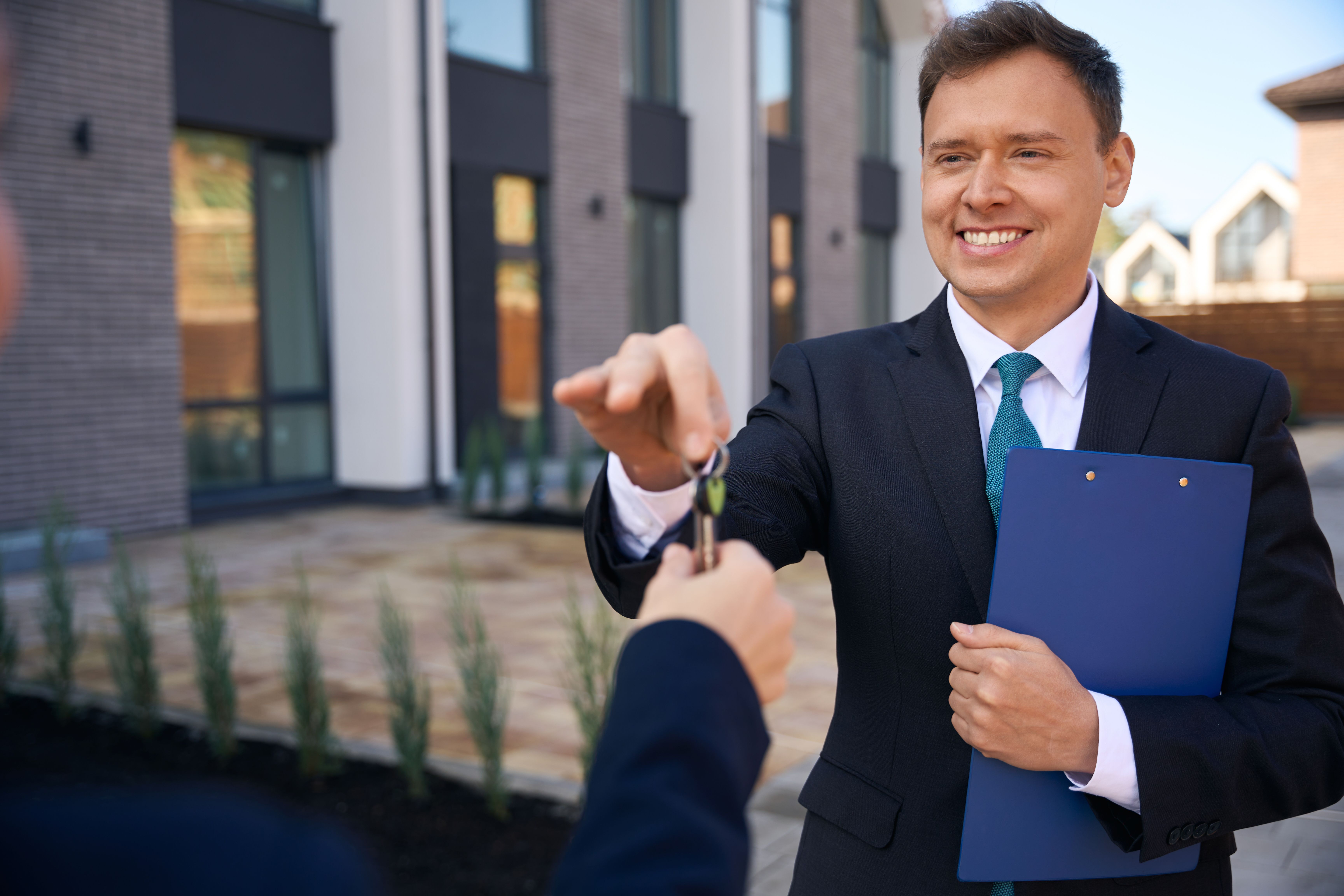 smiling-male-realtor-giving-keys-to-client-hand-2024-10-22-12-17-50-utc.jpg